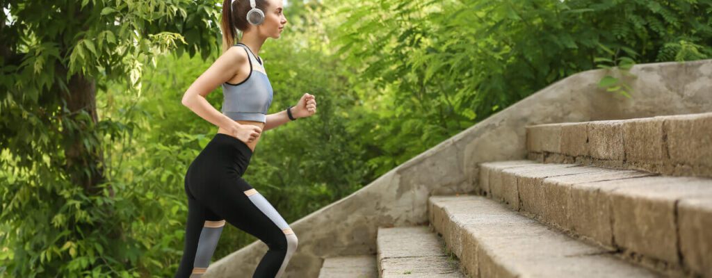 A woman running up some steps wearing headphones