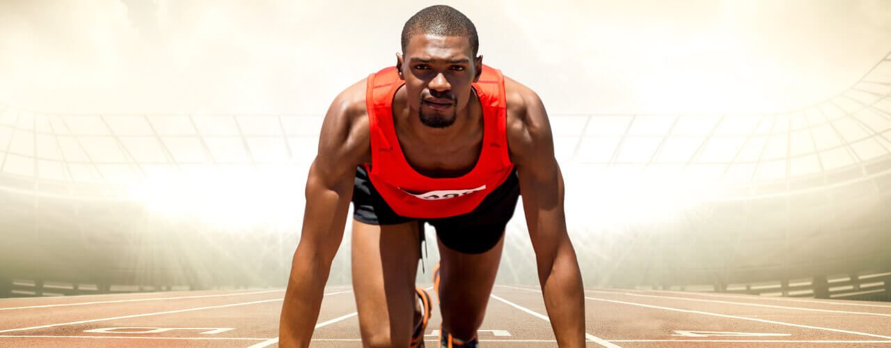 A man in red shirt and black shorts on top of a track.