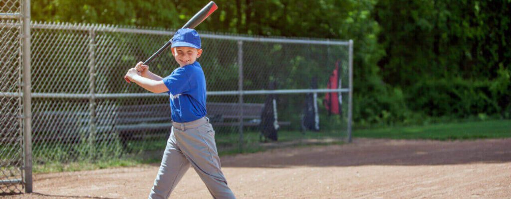 A young boy holding a baseball bat on top of a field.