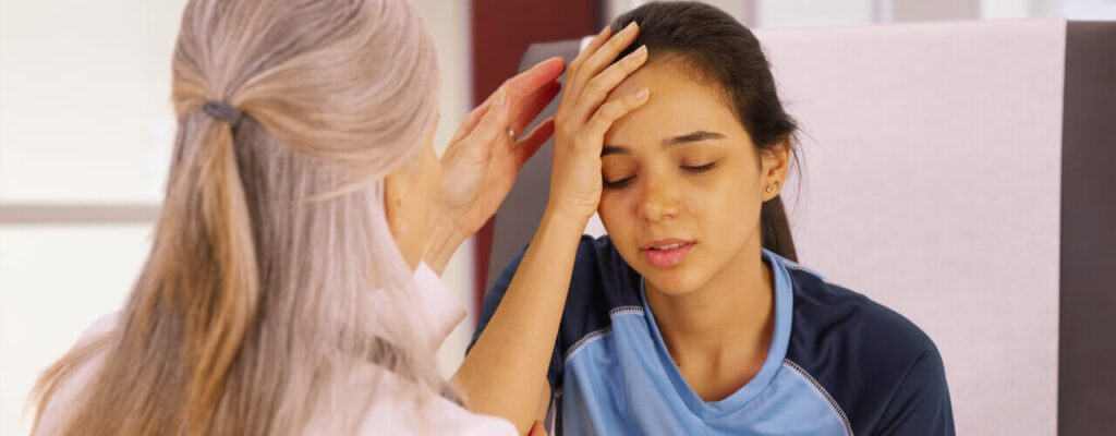 A woman is holding her head in front of another person.