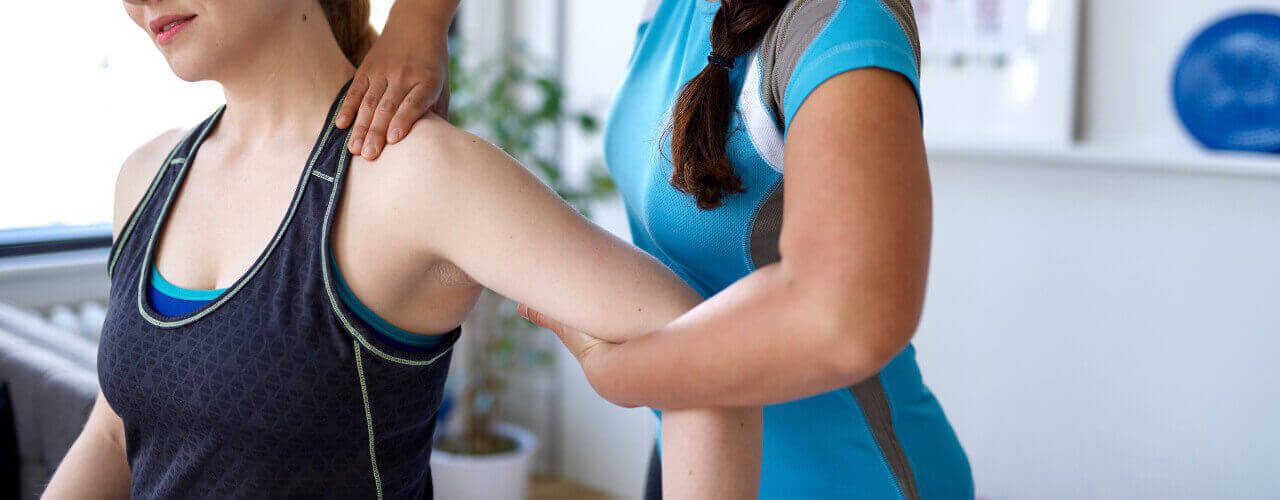 A person is holding their leg while another person holds her hand.
