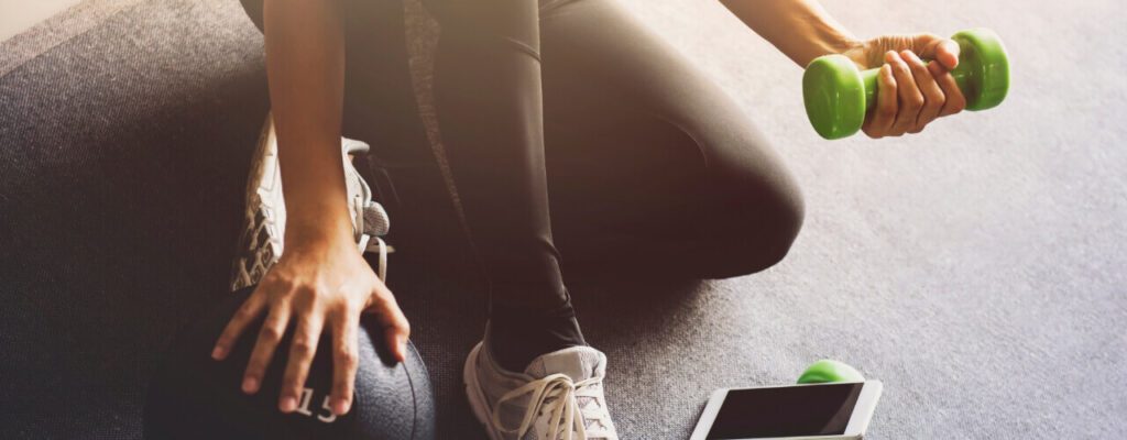 A person with white shoes and black pants is sitting on the floor.